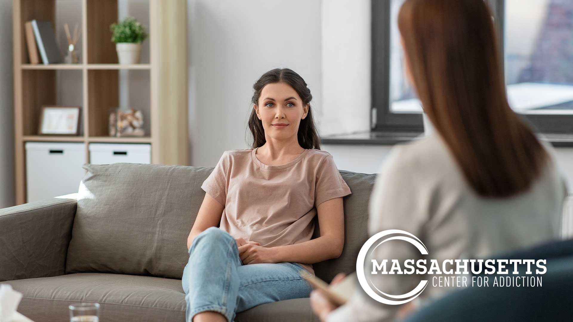 Female patient sitting on a couch in her therapist's office beginning a Solution-Focused Therapy session with a female therapist.