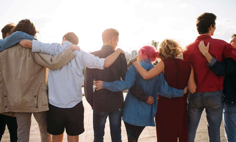 Group of men and women embracing one another outside to support their recovery journeys.