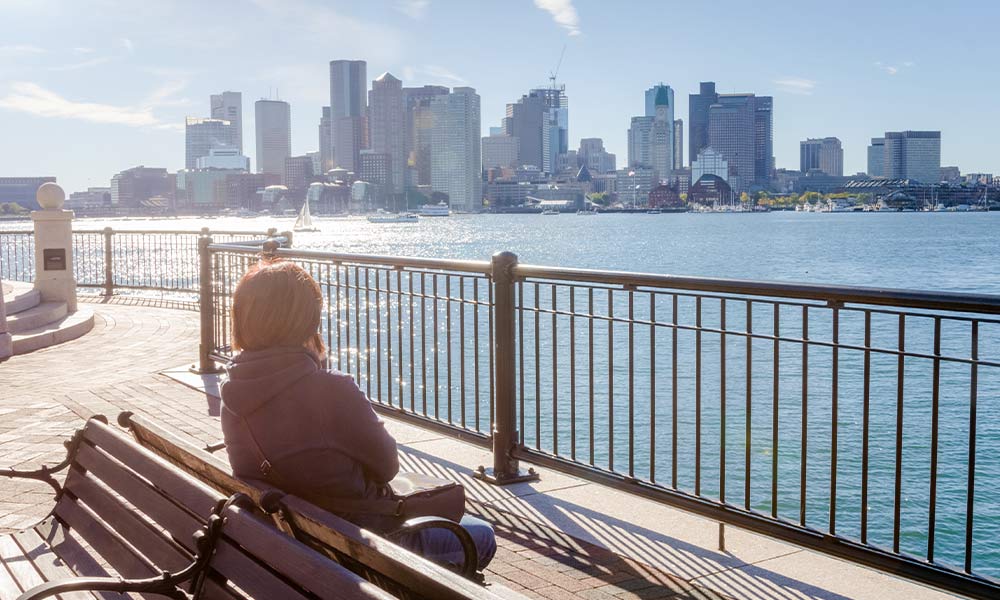 Woman sitting on a bench over looking the South Boston Harbor showing the search for the best drug and alcohol rehab.