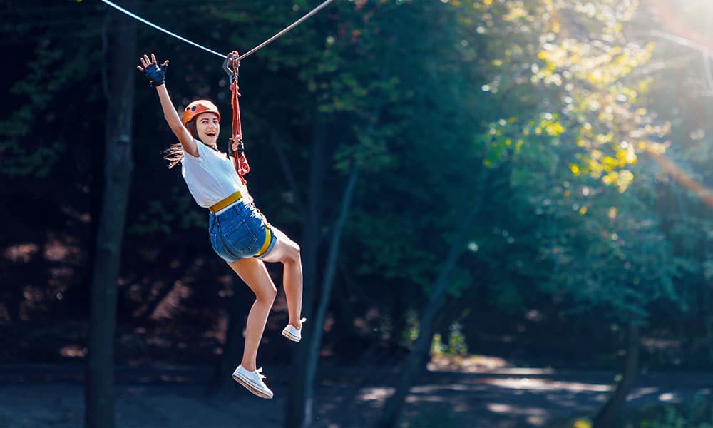 Woman smiling and enjoying herself while zip lining during experiential therapy session.