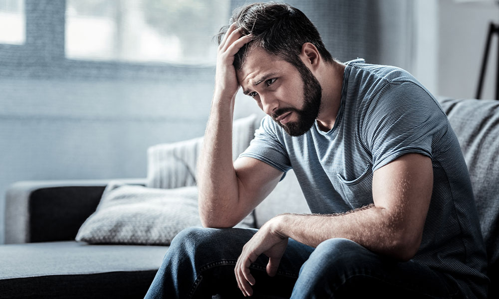 Distraught man sitting on the floor showing signs of depression